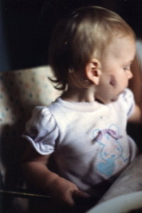Toddler Rebekah with a splotch of purple something on her cheek