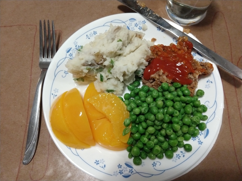 Meatloaf, mashed potatoes, green peas, and canned peaches